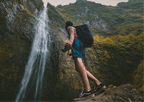 A photograph of a person exploring a waterfall.